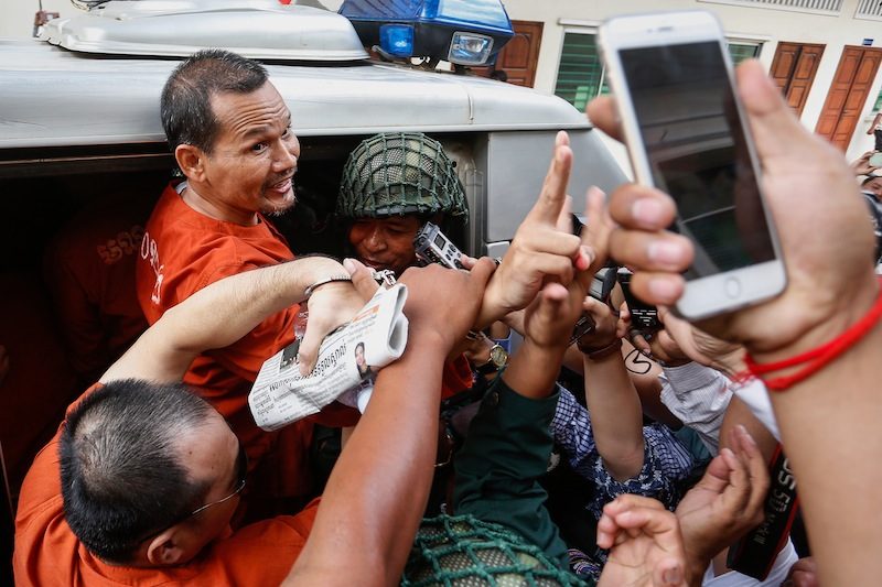Meach Sovannara, the imprisoned head of the CNRP’s information department, gestures at supporters as he is escorted into a police van following a hearing at the Appeal Court in Phnom Penh on Tuesday in the insurrection case against him and 10 other opposition activists and officials. (Siv Channa/The Cambodia Daily)