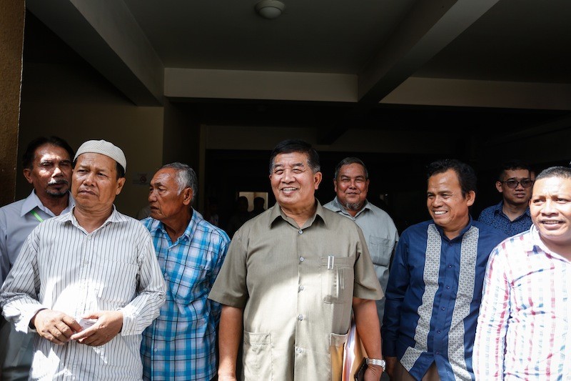 Secretary of State Ahmad Yahya, center, stands outside the Phnom Penh Municipal Court on Tuesday before his trial for allegedly defaming Secretary of State Othsman Hassan. (Siv Channa/The Cambodia Daily)
