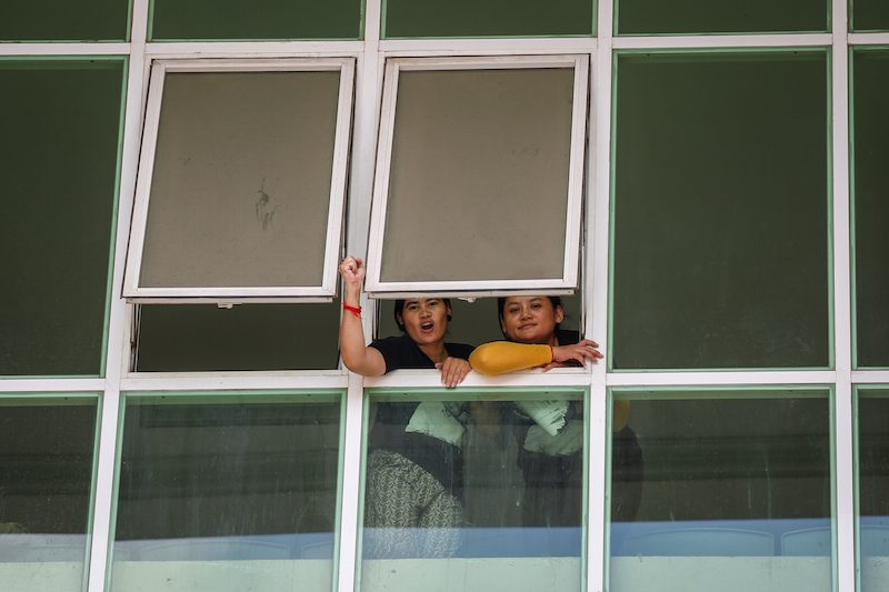 Activists Tep Vanny and Bov Sophea look out a window at the Phnom Penh Municipal Court on Wednesday afternoon. (Hannah Hawkins/The Cambodia Daily) 