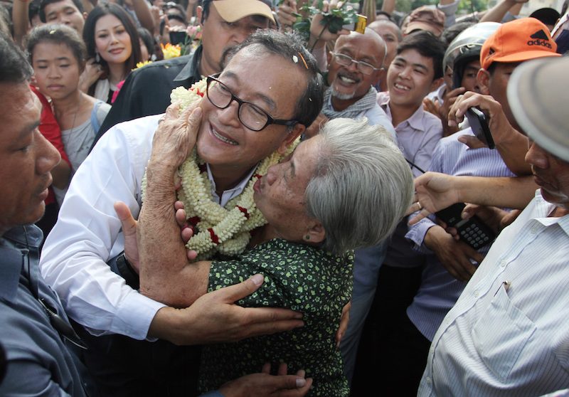 Opposition leader Sam Rainsy is embraced by a supporter during a visit to Phnom Penh's O'Russei market in September 2013. (Siv Channa/The Cambodia Daily)