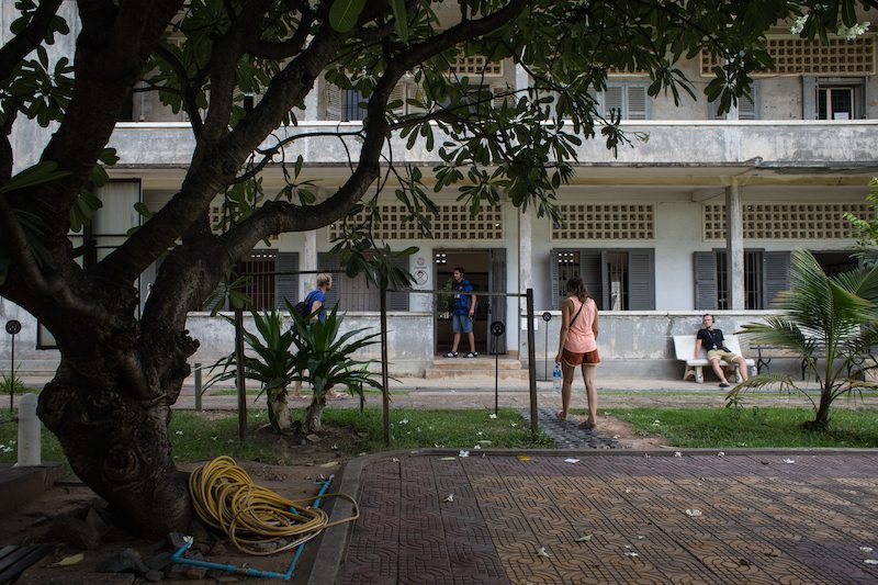 Tourists walk near a virtual Pokemon Go 'gym' located beneath a tree in the courtyard of Phnom Penh's Tuol Sleng Genocide Museum on Tuesday. (Hannah Hawkins/The Cambodia Daily)