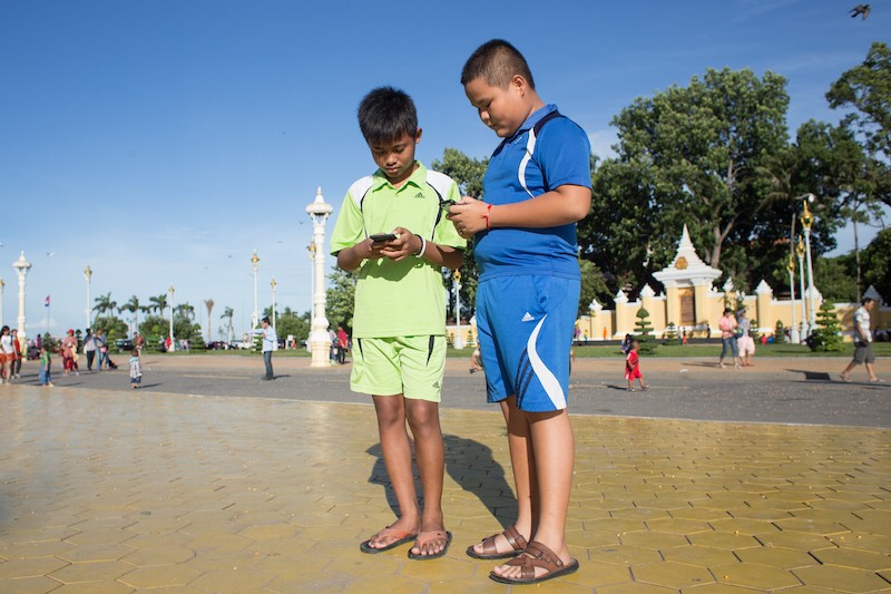 Nangsophan Mam, 13, left, and Sithiksak Leakhana, 12, play Pokemon Go in front of the Royal Palace in Phnom Penh on Sunday afternoon. (Hannah Hawkins/The Cambodia Daily)