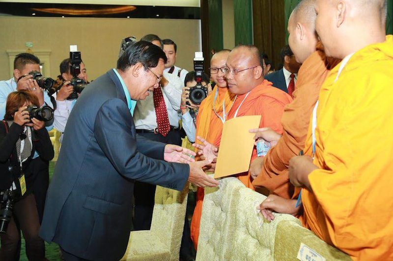 Prime Minister Hun Sen, in a photograph posted to his Facebook page, takes a petition from monks on Monday during a forum on the protection of Cambodia's natural resources at his office building in Phnom Penh.
