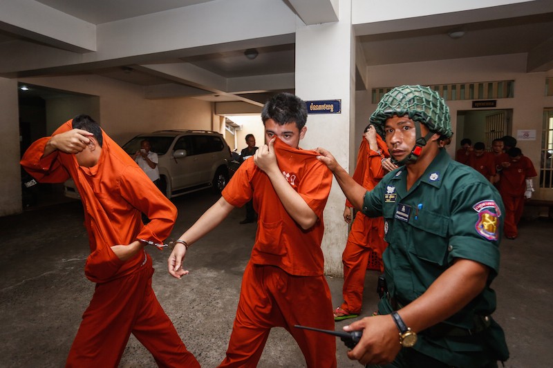 A suspect, center, in the fatal motorbike robbery of a  Phnom Penh man last year is escorted from the Phnom Penh Municipal Court yesterday. (Siv Channa/The Cambodia Daily)