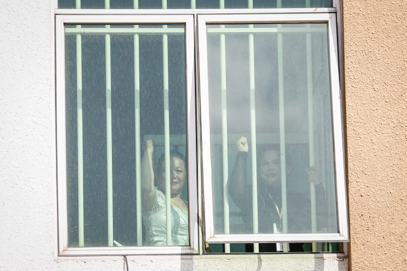 Activists Kong Chantha, left, and Bo Chhorvy gesture from inside the Phnom Penh Municipal Court on Monday morning. (Siv Channa/The Cambodia Daily)