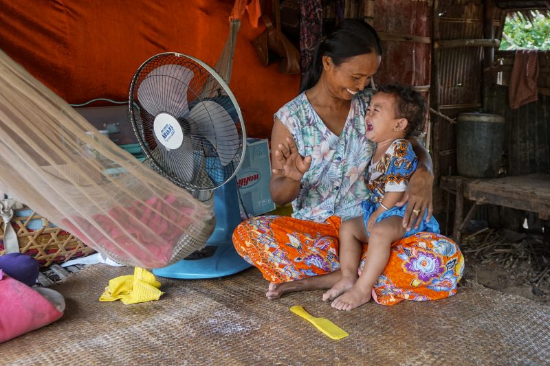 Om Mat holds her granddaughter at her home on the outskirts of Takeo’s provincial capital, Donkeo City. (Sonia Kohlbacher/The Cambodia Daily)