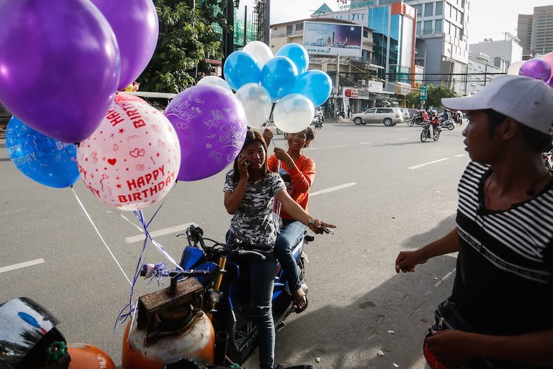 Young women buy balloons from a vendor near Phnom Penh's Independence Monument on Tuesday. (Siv Channa/The Cambodia Daily)