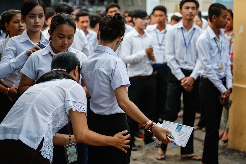 A student is frisked before entering Preah Sisowath High School in Phnom Penh to sit the national high school exit exam last month. (Siv Channa/The Cambodia Daily)