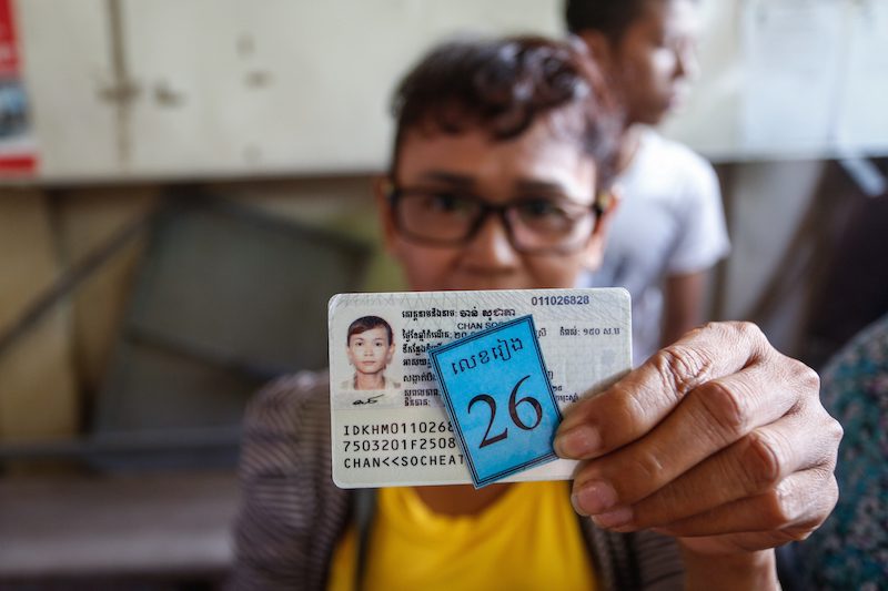 A woman holds up her new identification card after registering to vote in Phnom Penh earlier this month. (Siv Channa/The Cambodia Daily) 