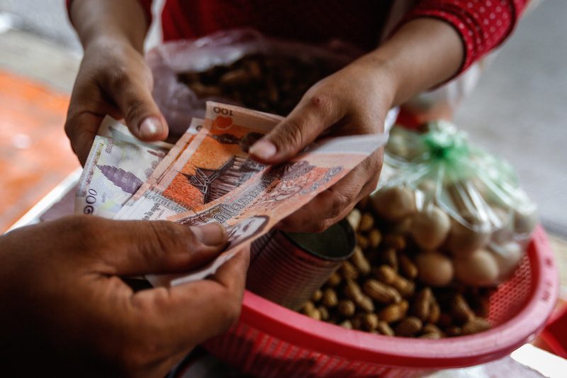 A man uses riel notes to purchase peanuts in Phnom Penh last month. (Siv Channa/The Cambodia Daily) 