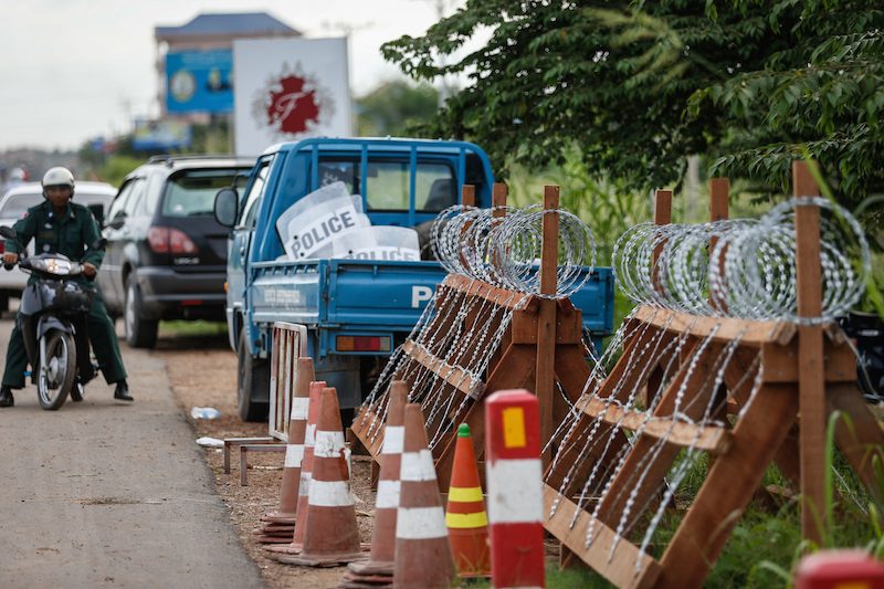 Razor-wire barricades and a police truck carrying riot shields sit on the side of National Road 6 in Kandal province on Thursday. (Siv Channa/The Cambodia Daily)
