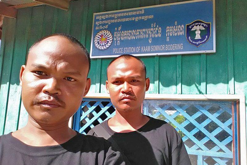 Chum Huor and Chum Huot pose in front of the Ka'am Samnor border police office in Kandal province in a photograph posted to their Facebook page.