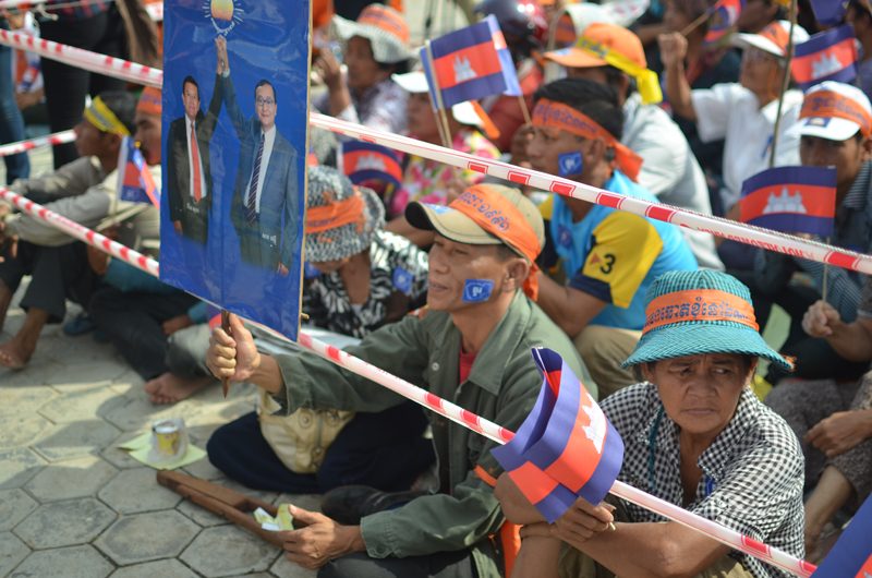 A protestor holds up a sign of opposition leaders Sam Rainsy and Kem Sokha during a CNRP demonstration in October 2013 marking the anniversary of the Paris Peace Agreements. (Lauren Crothers/The Cambodia Daily)