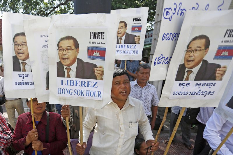 A protester holds signs calling for the release of opposition Senator Hong Sok Hour outside the Phnom Penh Municipal Court during his trial on Wednesday. (Siv Channa/The Cambodia Daily)