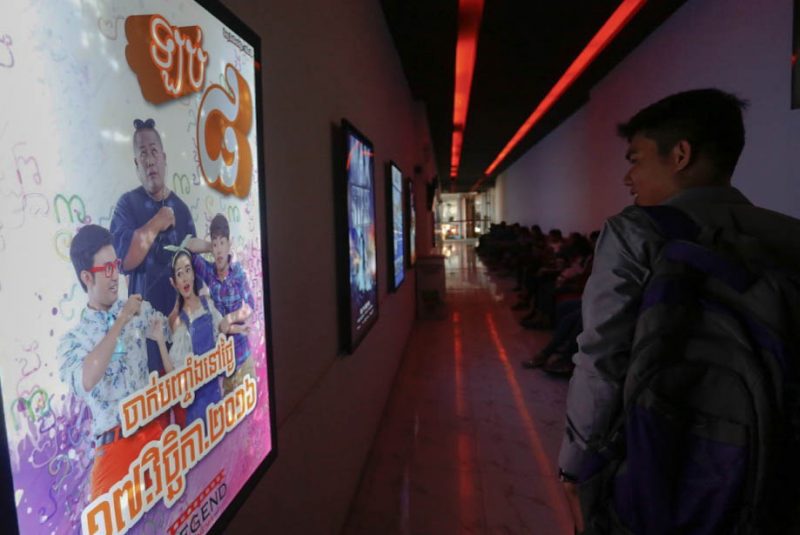 A man walks by an illuminated movie poster at Legend Cinema in Phnom Penh's City Mall on Wednesday. (Siv Channa/The Cambodia Daily)