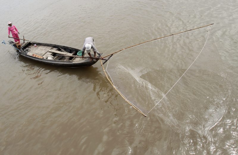 A man casts a fishing net into the Mekong River from a boat in Phnom Penh in December 2011. (Pring Samrang/Reuters)