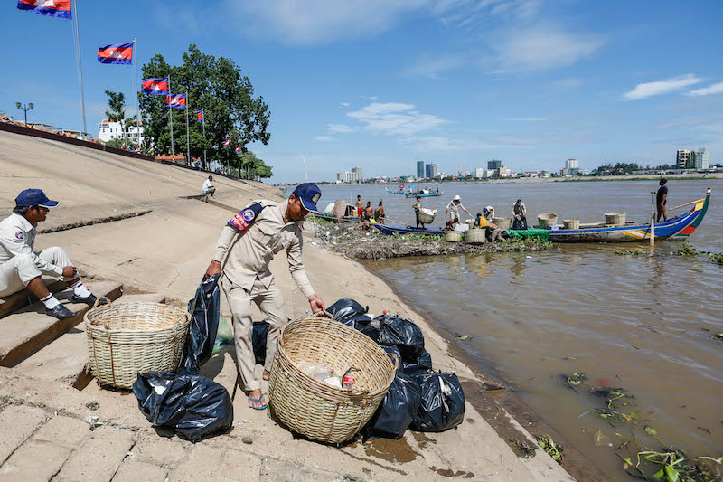 Daun Penh district security guards remove litter from the Tonle Sap River in Phnom Penh on Thursday. (Siv Channa/The Cambodia Daily)