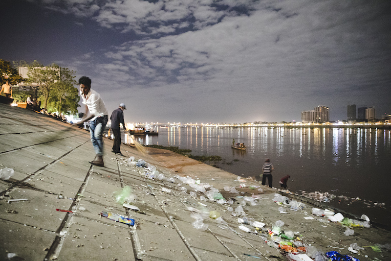 Men sweep trash left by Water Festival attendees along Phnom Penh's riverside on Monday. (Nick Sells Photography)