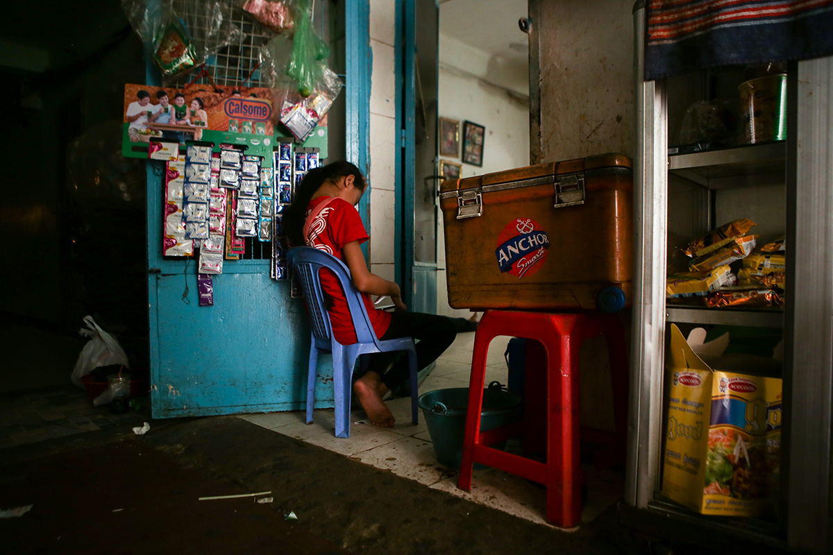 One of Ms. Savoeun’s daughters waits for customers in the doorway of their home. (Hannah Hawkins/The Cambodia Daily)