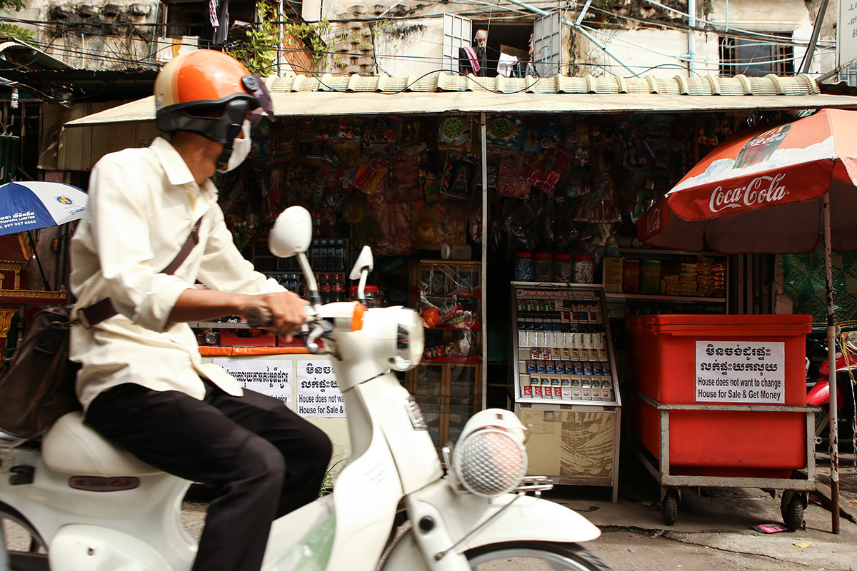 A motorist rides by one of the building’s shopfronts. (Hannah Hawkins/The Cambodia Daily)