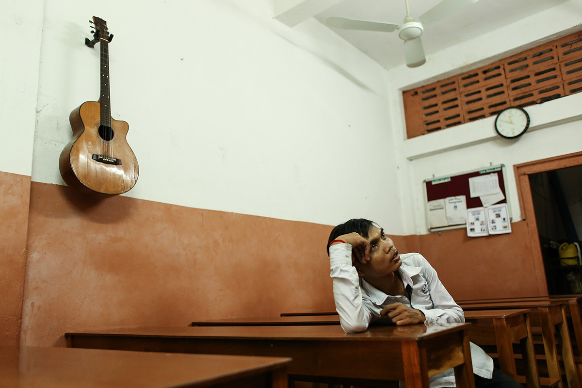 Chea Oun, a computer teacher at the Aziza school, sits at a desk in the school’s only classroom. (Hannah Hawkins/The Cambodia Daily)