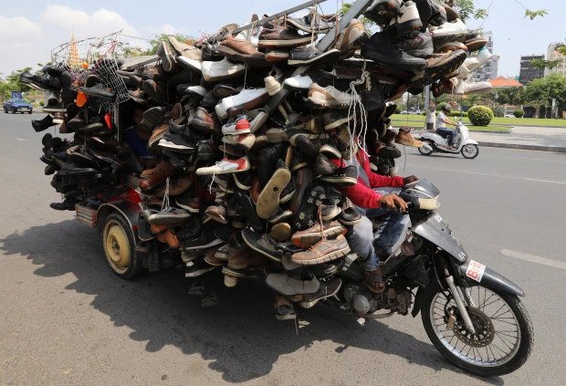 SOLE TRADER Cambodian salesman straps hundreds of shoes to motorcycle in bid to sell them